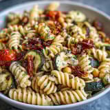 A vibrant bowl of chickpea pasta tossed with caramelized roasted vegetables and a luscious, garlicky tahini dressing.