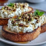 Creamy whipped ricotta toast drizzled with sweet honey, garnished with vibrant pistachios.