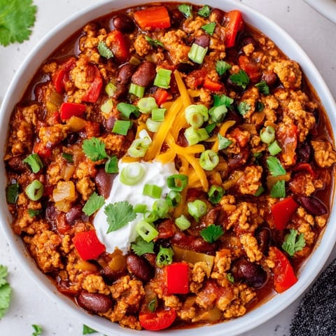 Close-up of hearty turkey chili simmering in a pot, featuring ground turkey, beans, tomatoes, and spices. 