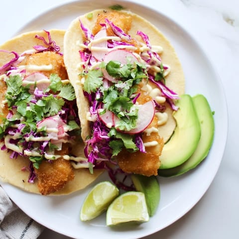 Crispy battered Baja Fish Tacos filled with flaky white fish, crunchy cabbage, and creamy lime sauce in warm corn tortillas.