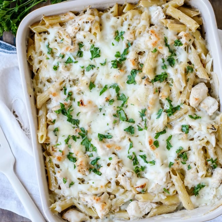 Golden-brown Chicken Alfredo Bake served in a white dish with parsley garnish.