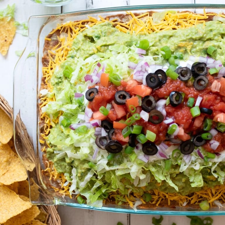 Cold Tex-Mex dip served in a glass dish with crispy tortilla chips for scooping.